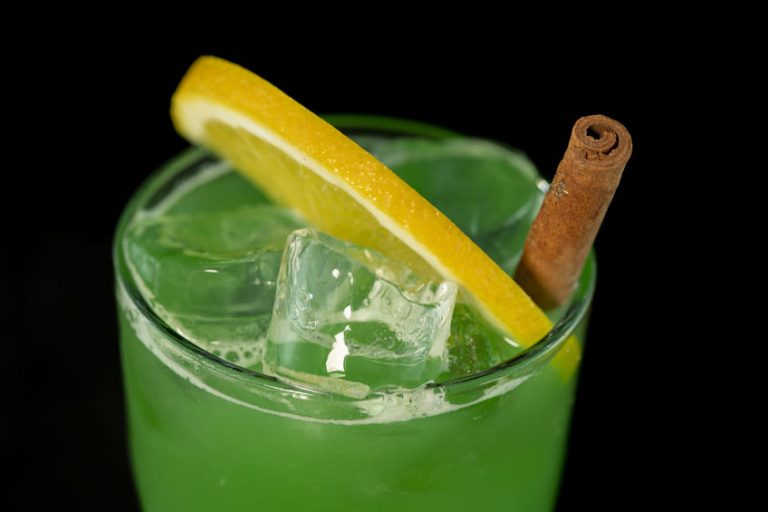 Green Cocktail with green juices, alcohol and lime wedge
